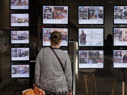 Una mujer ante el escaparate de una inmobiliaria en Barcelona.