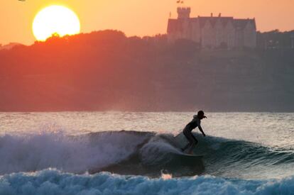 Surfeando en la playa de Somo con el Palacio de la Magdalena al fondo.