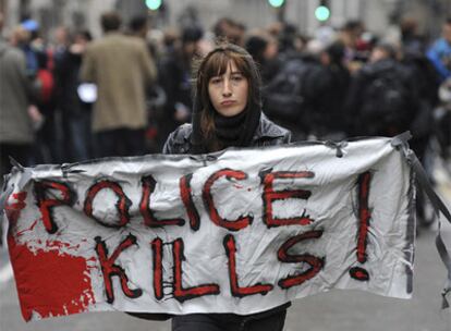 Una manifestante porta una pancarta en la que se puede leer 'La policía mata' durante la marcha en recuerdo al quiosquero fallecido en Londres durante las protestas del G-20.