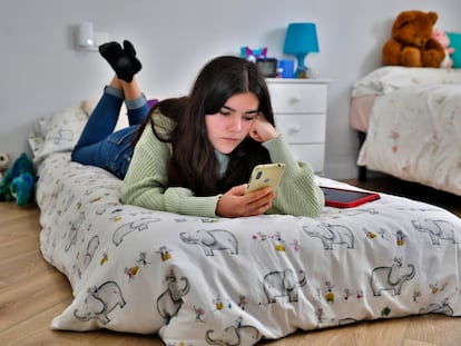 Cristina Barranco, de 14 años, confinada en casa de sus padres en Valencia, mira el móvil en su habitación.