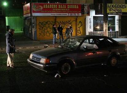 Un hombre observa un coche con agujeros de bala en el que se encontraron los cadáveres de dos policías el lunes en Tijuana.