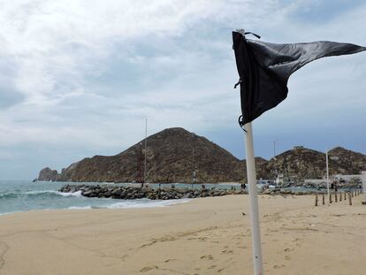 Una bandera negra, colocada para alertar a los turistas de olas altas y corrientes que no son seguras para nadar, se muestra en una playa de Baja California en México.