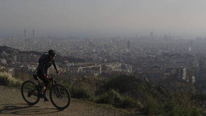 Una ciclista por la carretera de les Aigües, durante un episodio de contaminación. Al fondo, Barcelona.