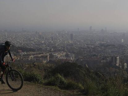 Una ciclista por la carretera de les Aigües, durante un episodio de contaminación. Al fondo, Barcelona.
