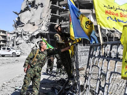 Membros das Forças Sírias Democráticas colocam sua bandeira na praça A o-Naim em Raqa nesta terça-feira.