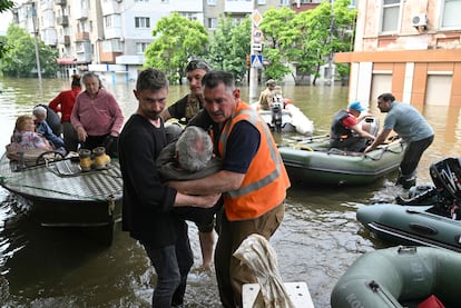 Un grupo de voluntarios ayudan a trasladar a un discapacitado durante una evacuación de un área inundada en Jersón, este jueves.
