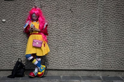 Un payaso revisa su teléfono mientras espera fuera de la Basílica de nuestra Señora de Guadalupe.