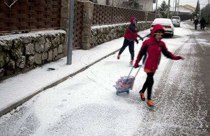 Dos niños camino del colegio tras caer los primeros copos de nieve en Manzanares el Real (Madrid).