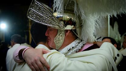 Un 'armao' de la Hermandad de La Macarena abraza a un nazareno en la basílica después de saber que no podrán hacer su estación de Penitencia a causa de la lluvia.