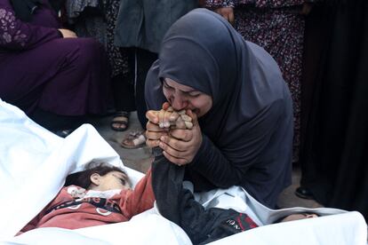 La madre de los gemelos de ocho años Ahmed y Jihan Nasser, muertos en un bombardeo israelí, besa sus manos en el hospital de Al Aqsa, al sur de la Franja, este viernes.