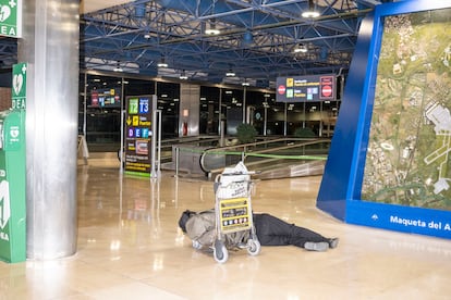  Una persona duerme en los pasillos que conectan la terminal 1 y 2 de Barajas durante la madrugada del lunes. 