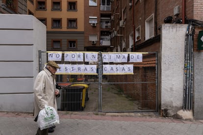 Un hombre pasa por delante de los edificios afectados por la operación de transporte de maquinaria, en la calle de Cavanilles de Madrid.