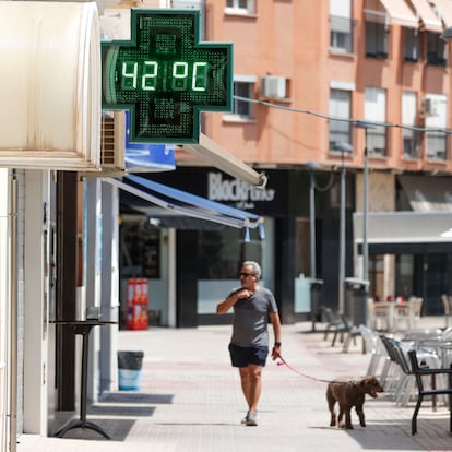 GRAFCVA8909. XÀTIVA (VALENCIA), 11/08/2025.- La Agencia Estatal de Meteorología (Aemet) ha anunciado que este lunes y el martes serán, con toda probabilidad, los días más cálidos del verano en la Comunitat Valenciana, y ha activado el aviso naranja por temperaturas de 40 grados en el interior sur de Valencia y de 39 grados en el litoral de esta provincia, y el aviso amarillo por lluvias de 20 l/m2 en una hora en el interior sur de Castellón y el interior norte de Valencia y tormentas en las mismas zonas con probable granizo y rachas muy fuertes de viento. En la imagen un hombre pasea con su perro ante un termómetro urbano que marca una temperatura de 42º en la localidad valenciana de Xàtiva. EFE/Manuel Bruque
