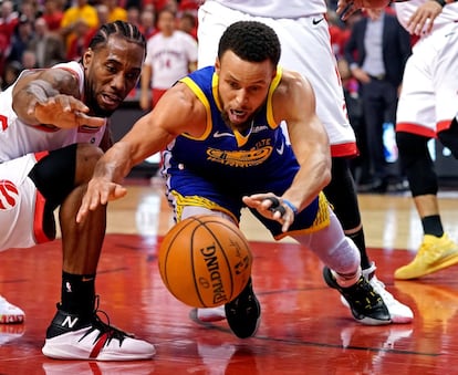 El jugador de Golden State Warriors Stephen Curry y el de Toronto Raptors Kawhi Leonard luchan por el balón durante el partido.