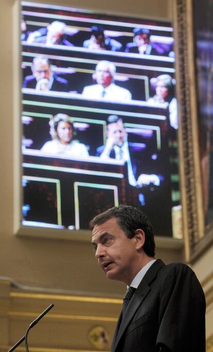 El presidente del Gobierno, José Luis Rodríguez Zapatero, se dirige al hemiciclo, con la imagen de Rajoy proyectada en el monitor central de la Cámara.