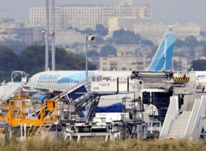 Técnicos del aeropuerto París-Orly trabajan en el avión que se ha incendiado cuando realizaba las primeras maniobras antes del despegue.