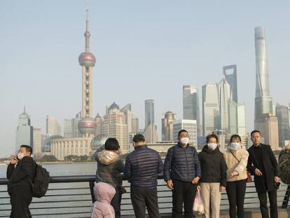 Visitantes con máscaras protectoras posan frente al Bund, el centro financiero de Shanghái.