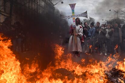 Un manifestante disfrazado de Jesús sujeta una cruz en la que se lee "Amor, no guerra", durante las protestas de este martes en París.