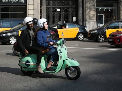 Usuarios de motos de alquiler por minutos de la empresa YeGo circula por la Via Laietana de Barcelona.