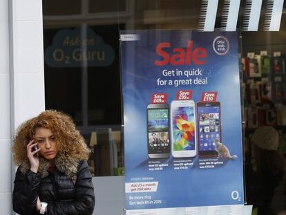 Una persona habla con su mp&oacute;vil frente a una tienda de O2 en Reino Unido