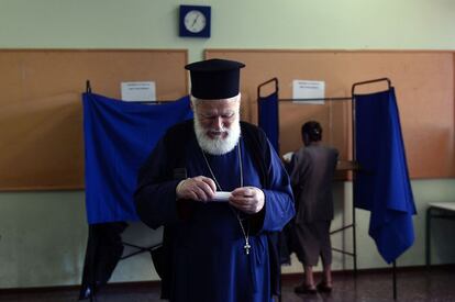 Un sacerdote ortodoxo prepara este domingo el sobre para emitir su voto en el referéndum griego en un colegio electoral en Atenas.