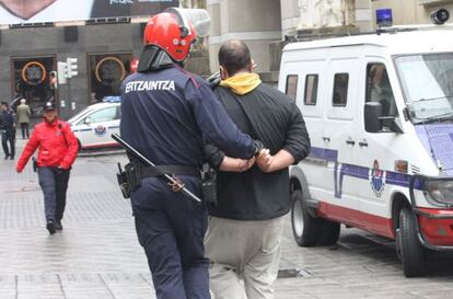 Un 'ertzaina' conduce a uno de los antifascistas arrestados en los incidentes de Bilbao.