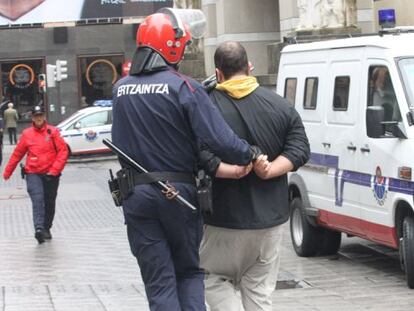 Un 'ertzaina' conduce a uno de los antifascistas arrestados en los incidentes de Bilbao.