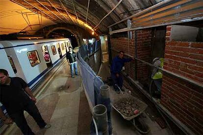 Una endeble valla separa a los pasajeros del metro de los operarios (uno de ellos sin casco) de las obras de reforma de  Legazpi.