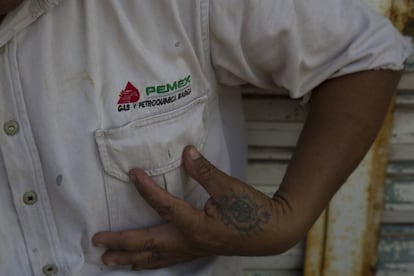 Un hombre muestra su camisa de Pemex.