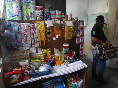 Funcionário do Ministério da Saúde de El Salvador fumega uma casa.