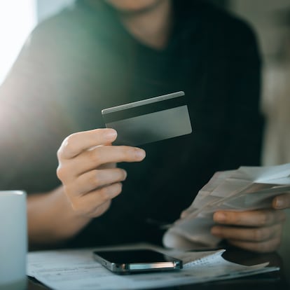 Cropped shot of young Asian woman holding credit card and expense receipts, handing personal banking and finance at home. Planning budget, calculating expenses and managing financial bills. Home budgeting. Home finances. Digital banking habits