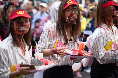 Tres mujeres caracterizadas como trabajadoras zombies de una conocida hamburguesería participan en un desfile de Halloween en Kawasaki (Japón), el 28 de octubre de 2018.