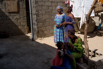 Mbayam Diop y su amiga Aïbatou, de pie en el patio de la casa familiar de la primera. Sentadas, una vecina trenza el pelo de una de las niñas de la casa. En la región de San Luis, la media de personas por hogar es ocho.