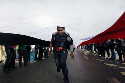 Un manifestante corre debajo de una gran bandera de Egipto durante las protestas en la plaza de Tahrir de El Cairo (Egipto), 2 de julio de 2013.
