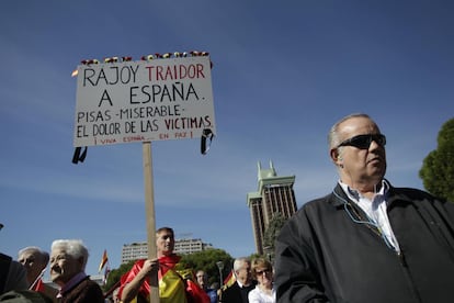 Un hombre envuelto en una bandera española, porta una pancarta contra Rojoy.