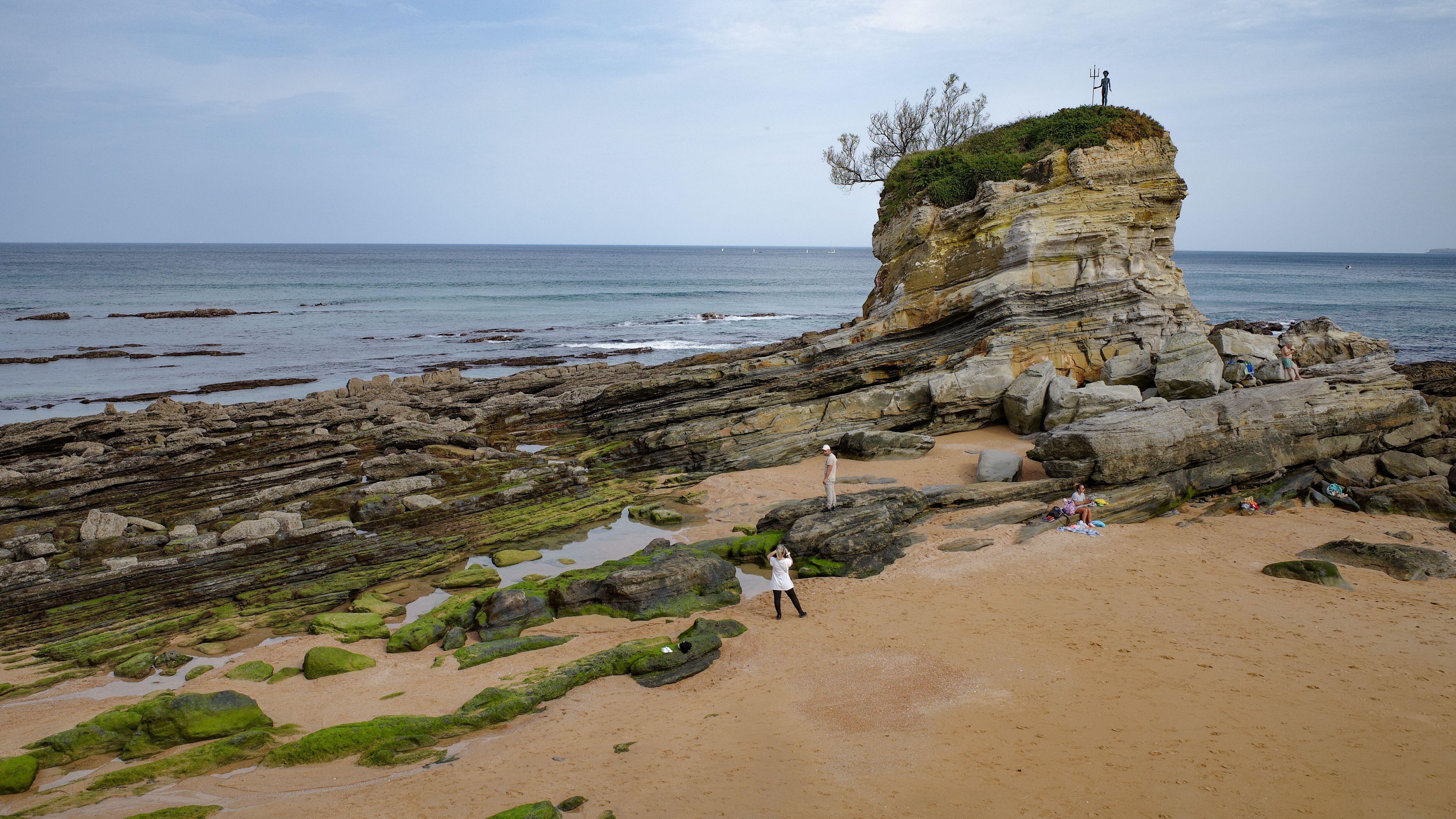 La delicada escultura 'Neptuno niño' en un promontorio de la playa del Camello, en Santander.