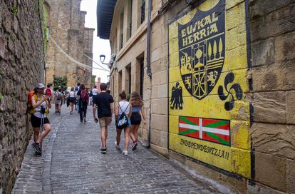 Un grupo de jóvenes pasa delante de un mural a favor de la independencia en una calle de Pasajes de San Juan (Gipuzkoa).