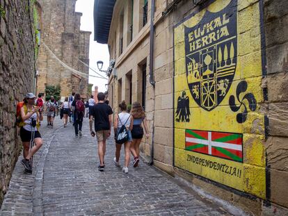 Un grupo de jóvenes pasa delante de un mural a favor de la independencia en una calle de Pasajes de San Juan (Gipuzkoa).