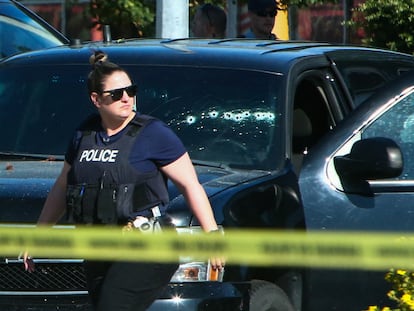 Una agente junto a un vehículo con varios impactos de bala, este lunes en la localidad de Langley, en la Columbia Británica (Canadá).