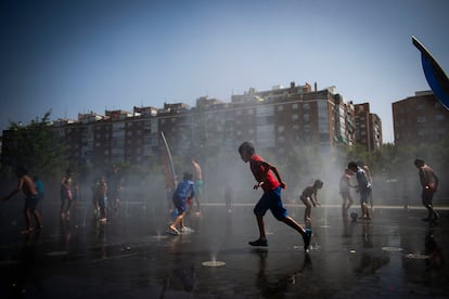 Varios niños se refrescan en el parque de Arganzuela. 