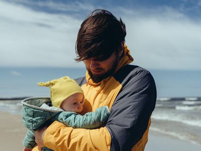 Un padre pasea con su bebé por una playa.