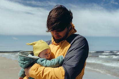 Un padre pasea con su bebé por una playa.