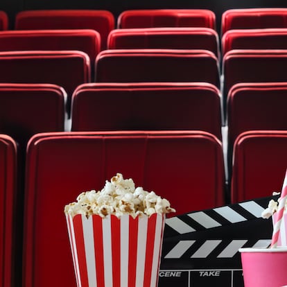 Stock photo showing close-up view of popcorn in two striped cardboard cartons surrounded by spilled popped kernels. Popcorn is a popular snack eaten in movie theatre cinemas.