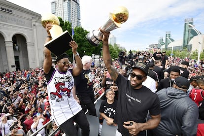 Kyle Lowry, de los Toronto Raptors, sostiene el trofeo de Larry O'Brien, mientras que el delantero Kawhi Leonard alza su trofeo de jugador más valioso durante el desfile de la victoria del equipo del campeonato de baloncesto de la NBA en Toronto.
