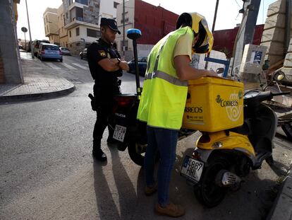 Un agente de la Policía Nacional escolta a un cartero que reparte la documentación para votar por correo en el barrio de La Libertad, en Melilla, en la tarde de este jueves.