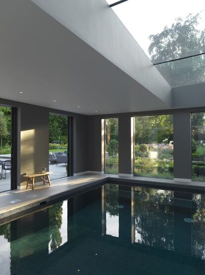 Una piscina interior con vistas al jardín a la que se accede desde la cocina. El banco de roble junto al agua es de Another Country.