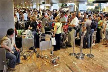 Los viajeros hacen cola en los mostradores del aeropuerto de El Prat (Barcelona).