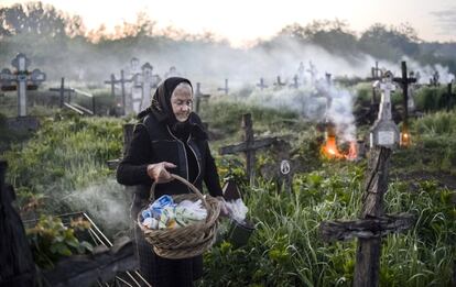 Una anciana lleva una cesta después de encender un fuego cerca de una tumba en la aldea de Copaciu, Rumania meridional. El Jueves Santo, durante la Semana Santa, muchos rumanos visitan las tumbas de sus seres queridos, encienden fuegos y comparten comida con los miembros de la comunidad en la memoria de los difuntos.