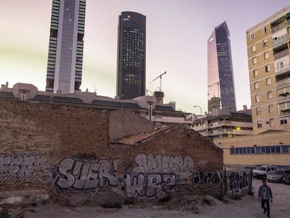 Un hombre camina por un poblado chabolista junto a las vías del tren en Chamartín, cerca de las Cuatro Torres del distrito financiero de Madrid.