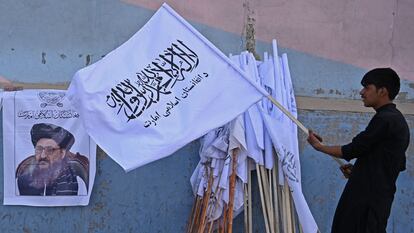 Un vendedor sostiene una bandera de los talibanes junto a una imagen del mulá Baradar, en Kabul. AAMIR QURESHI / AFP